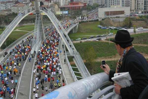Una persona observa como los corredores atraviesan el Puente Milenio.