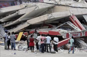  Varias personas observan el estado de un edificio en Puerto Príncipe. (Foto: Orlando Barría)