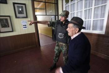 Un militar le da indicaciones a un hombre para votar.