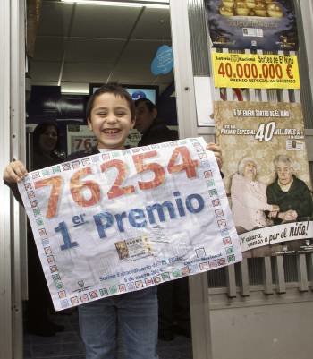 Un niño de Monforte sostiene el cartel que indica la venta del primer premio en la localidad lucense. (Foto: ELISEO TRIGO)