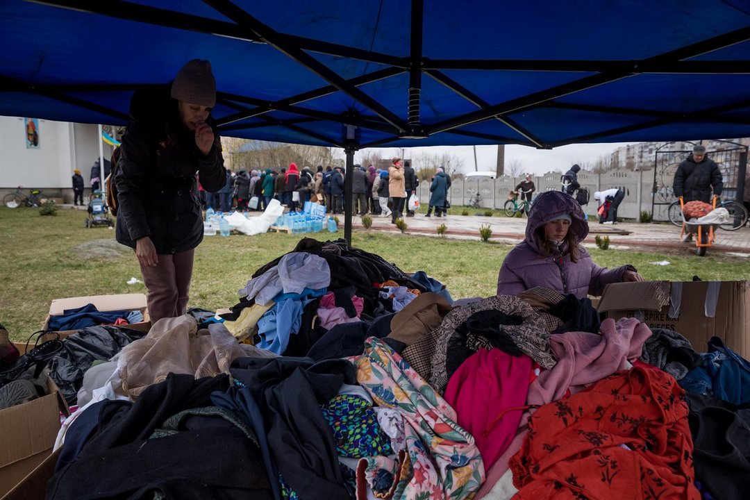 Varias personas buscan entre un montón de ropa donada, en Borodianka (Ucrania).