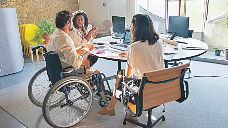 Tres personas, una de ellas con discapacidad, celebran una reunión de trabajo.