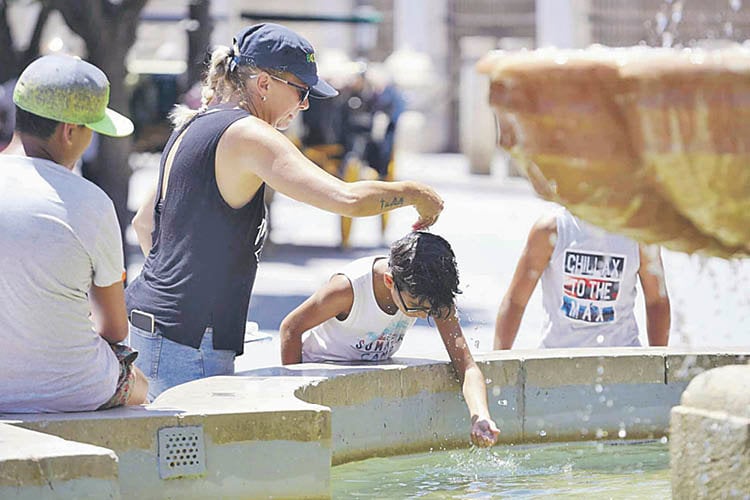 Una madre le echa agua a su hijo, por la cabeza, en una ola de calor del pasado verano.
