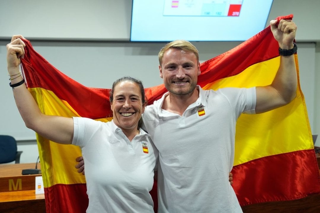 Támara Echegoyen y Marcus Cooper, con la bandera española en la sede del Comité Olímpico Español.